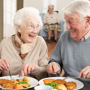 Older couple eating healthy meal while wearing dentures