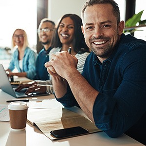 Younger man smiling at work with his colleagues