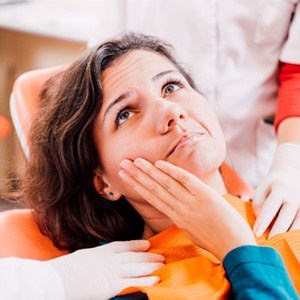 Woman wincing and looking at her dentist