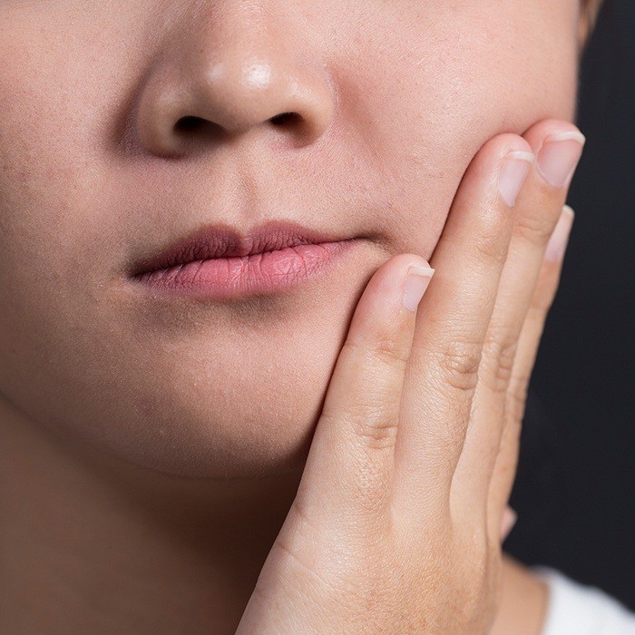 Young person with toothache holding cheek