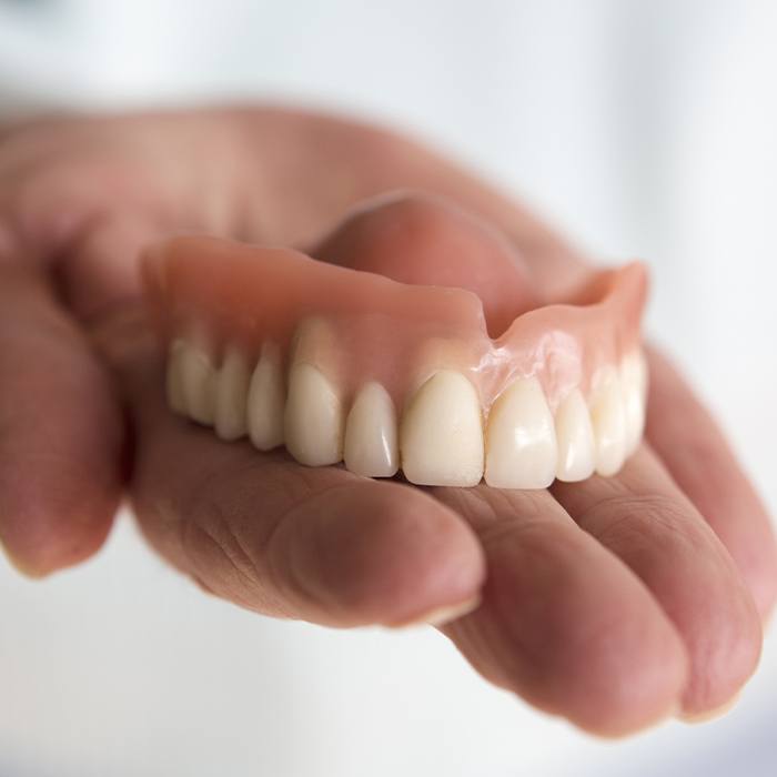 Hand holding a full denture