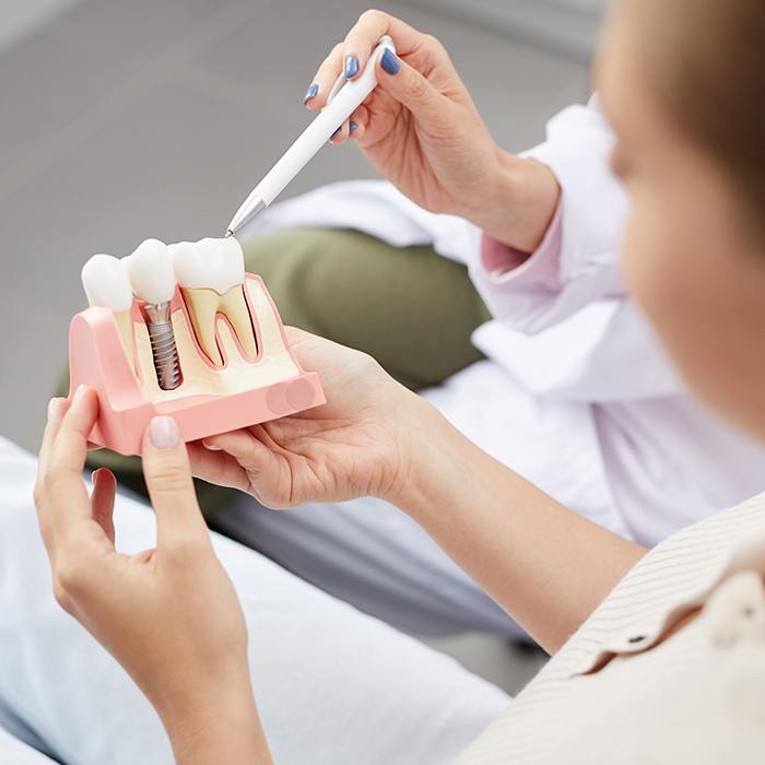 Dentist showing patient dental implant model