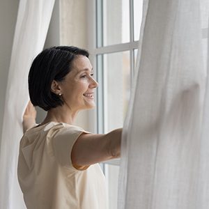 a woman smiling with dentures while looking out the window