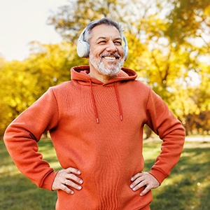 a man with dentures and headphones smiling outside