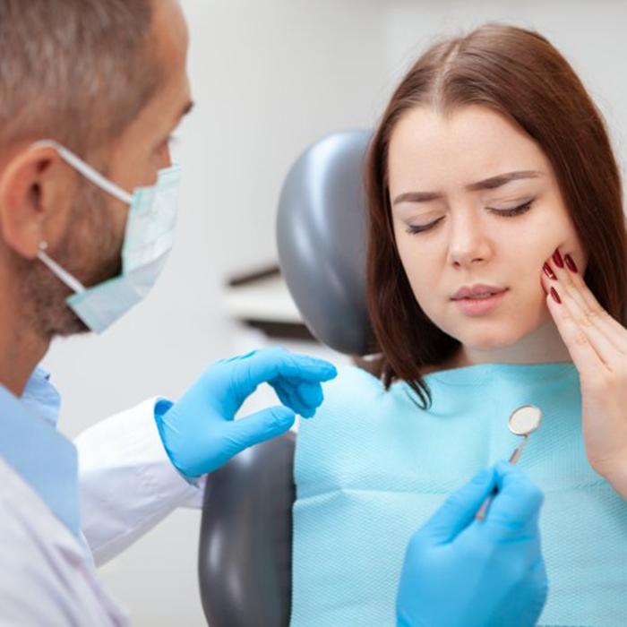 woman holding her cheek in pain while visiting an emergency dentist in Frisco