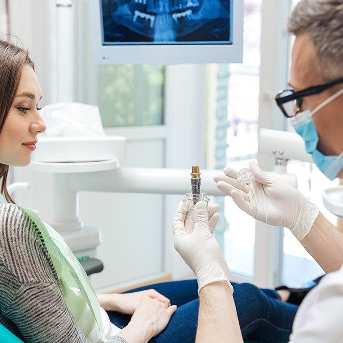 Dentist showing patient a dental implant model