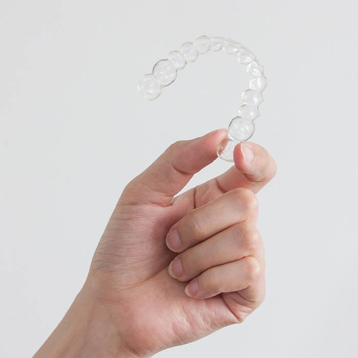 Hand holding clear Invisalign tray