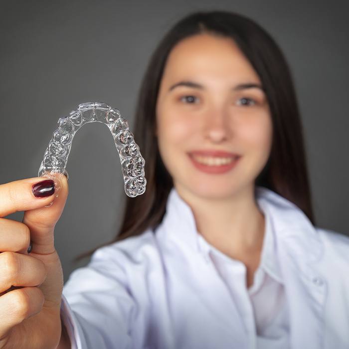 Woman holding up Invisalign tray