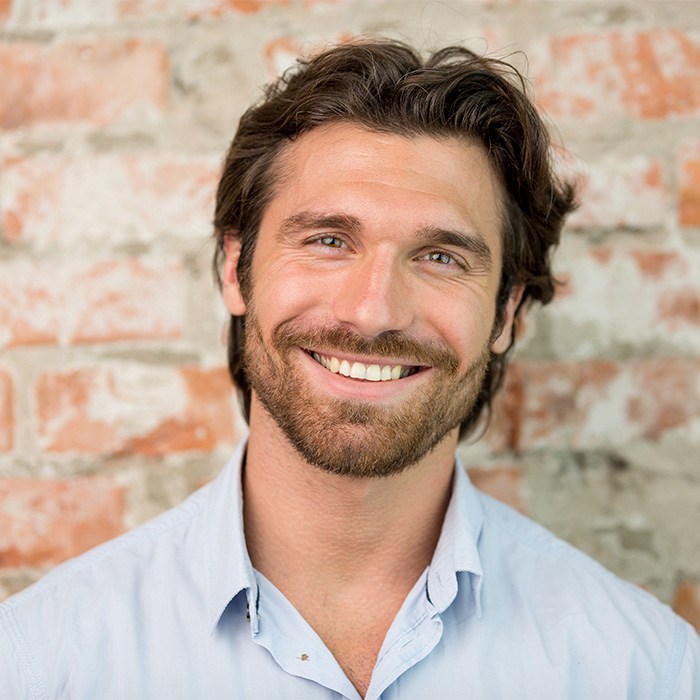 Man standing in front of wall smiling