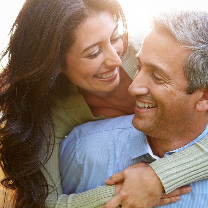 Man and woman smiling after dental implant tooth replacement