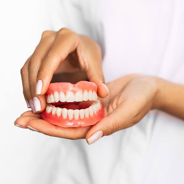 Hand holding full set of dentures