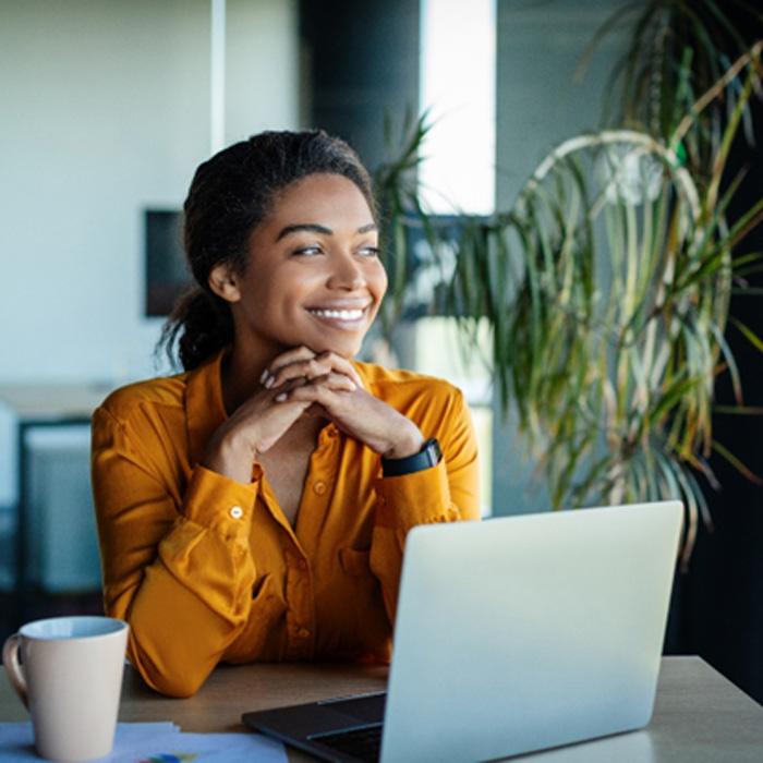 Woman in orange shirt smiling while working at office