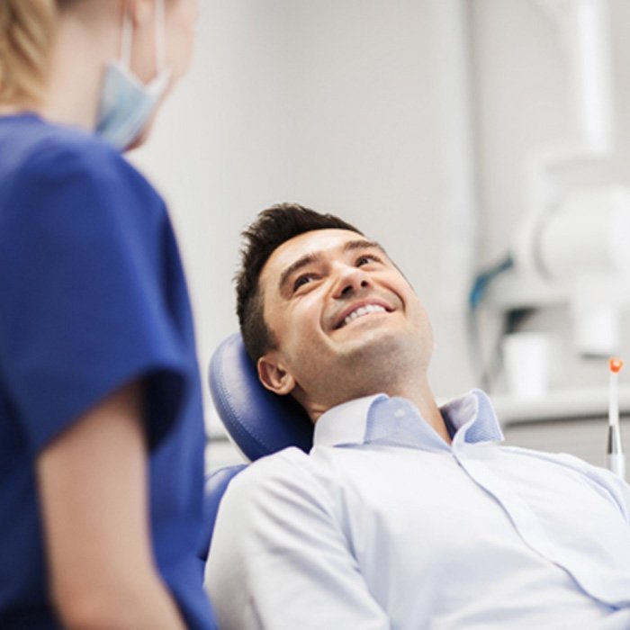 Patient smiling at dental assistant while sitting in treatment chair