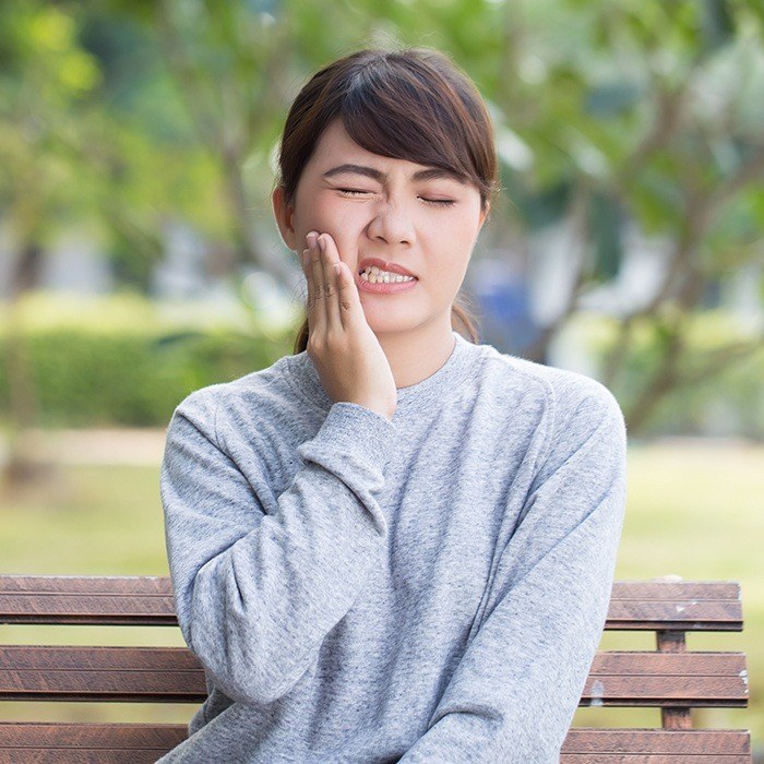 Woman in need of root canal therapy holding jaw