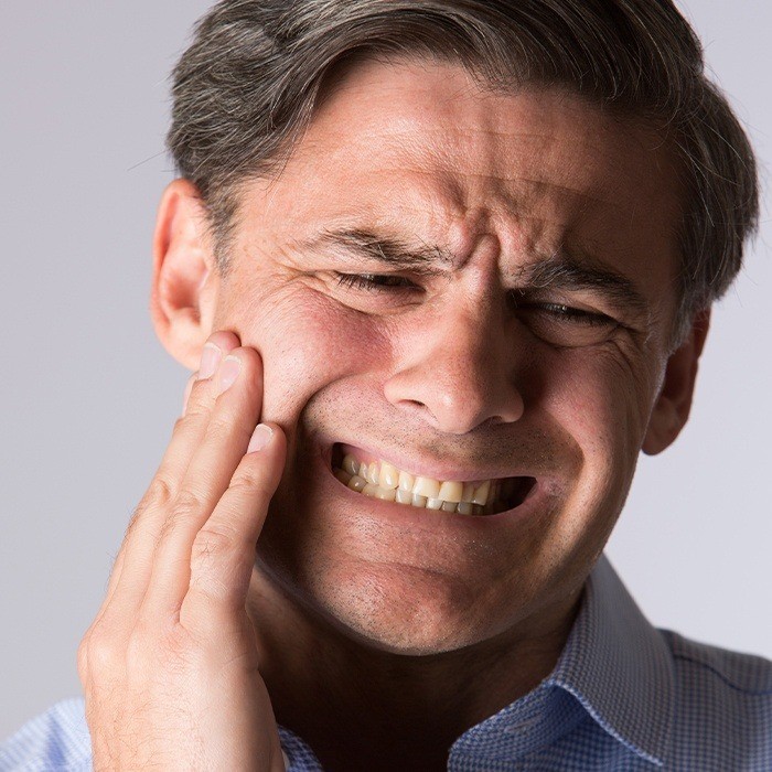 Man in need of T M J treatment holding jaw