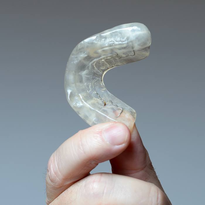 Hand holding a T M J therapy occlusal splint