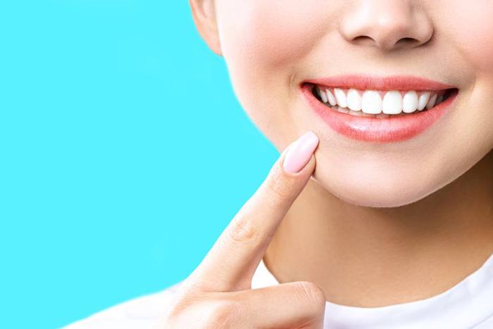 Close-up of woman pointing at her bright, white smile