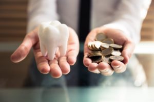 Frisco dentist holds large model tooth and pile of coins