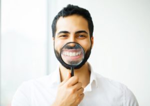 man using magnifying glass to show off his cosmetic dentistry work 