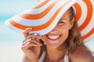 Woman in sun hat with beautiful smile thanks to cosmetic dentistry