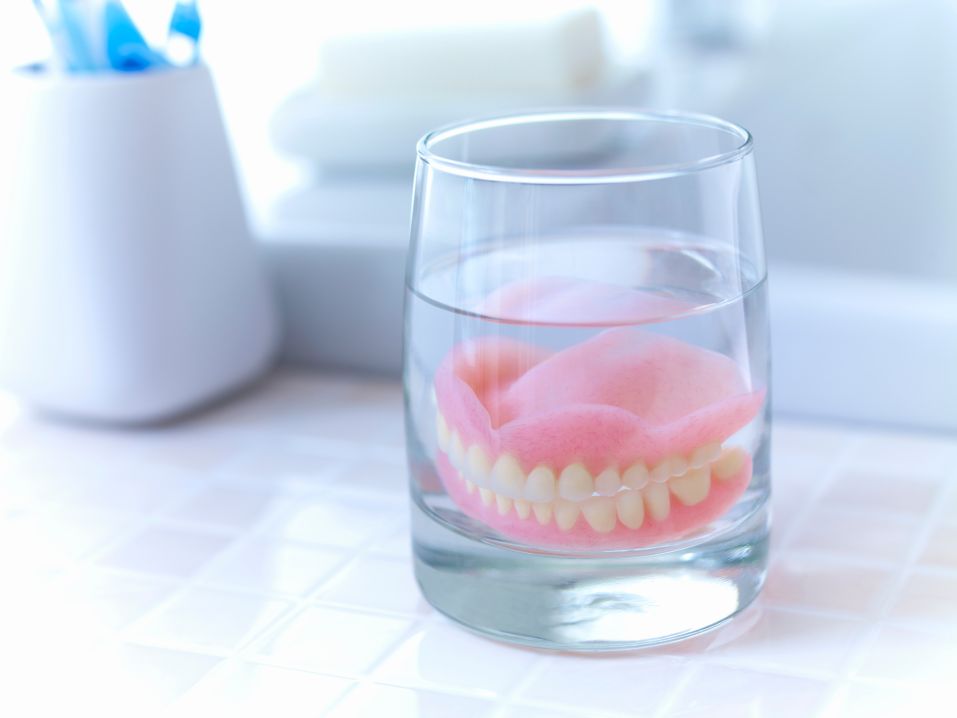 Dentures soaking in a glass of water.