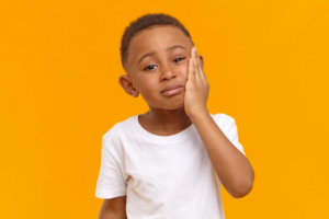 Child holding his cheek and jaw because of a toothache